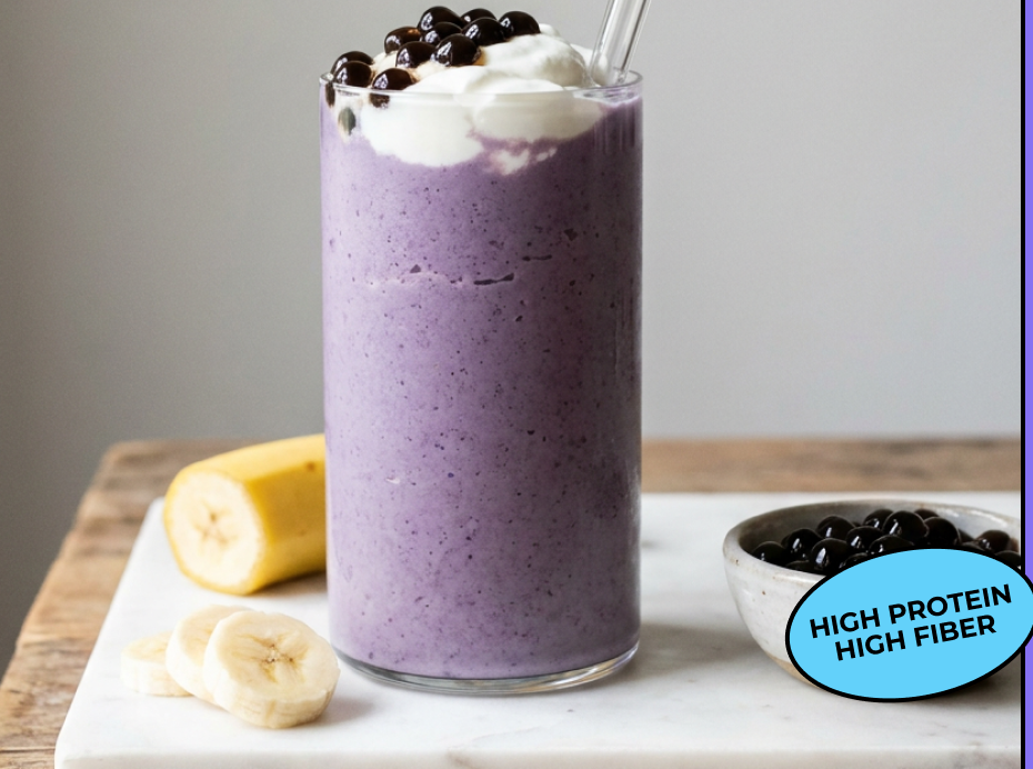 A tall glass of creamy taro banana protein shake topped with cream and boba pearls